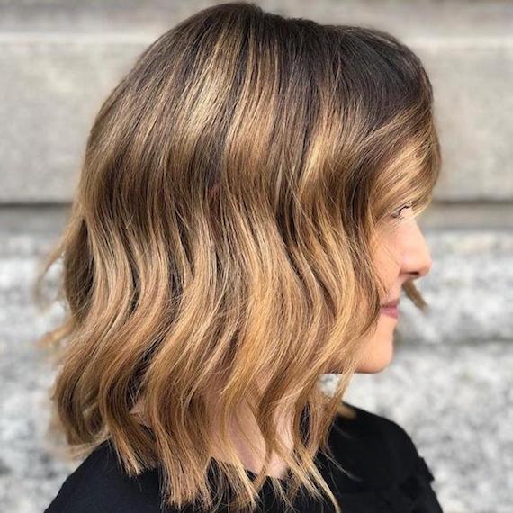 Ecaille blonde highlights through short, wavy, brown hair, created using Wella Professionals.