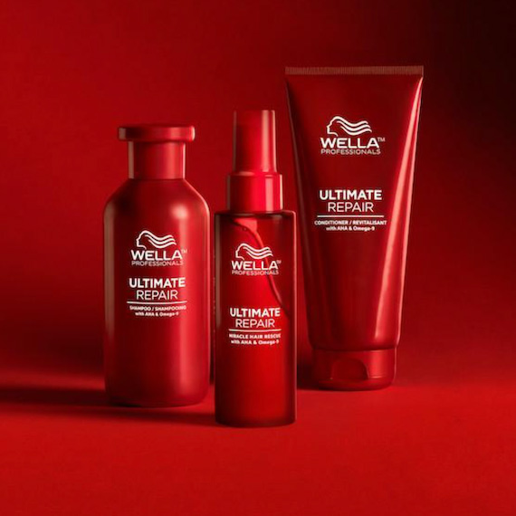 Wella Professionals Ultimate Repair Shampoo, Treatment and Conditioner stood in a line in front of a red backdrop