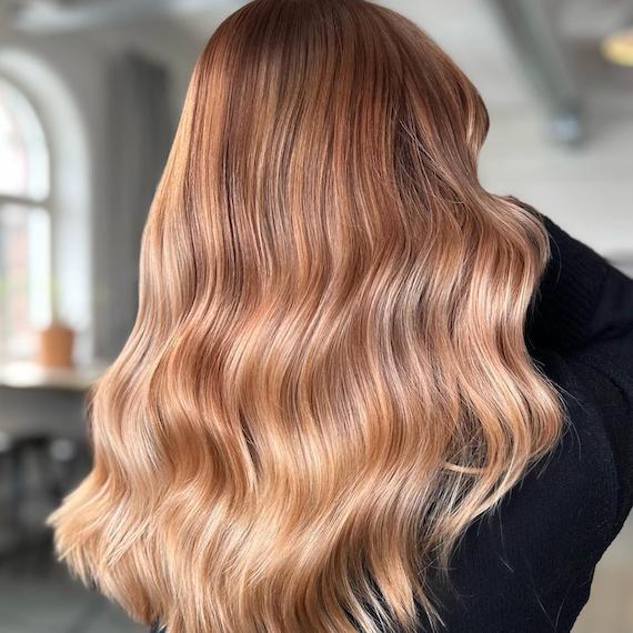 A person faces away from the camera to show their full head of strawberry blonde ombre hair