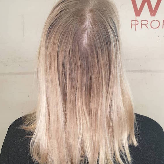 Foto von der Rückseite des Kopfes einer Frau mit blonden Haaren und dunklen Ansätzen.