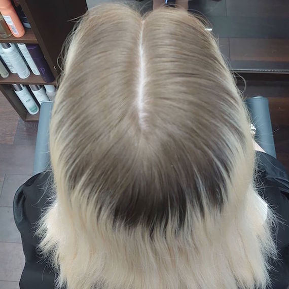 Photo of the back of a woman’s head with blonde hair and dark roots.