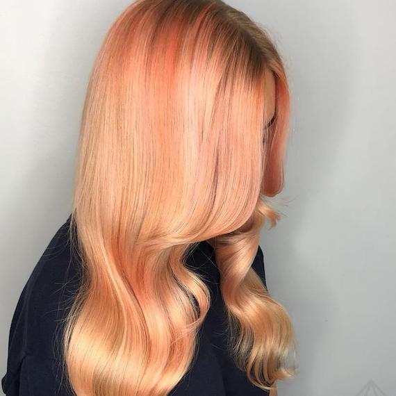 Side profile of woman with blorange and peach hair styled in a blow-dry.