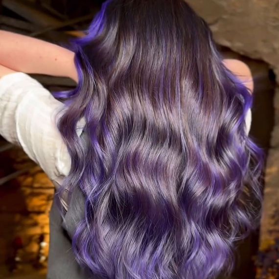 Long, dark, wavy hair with blue-purple highlights.