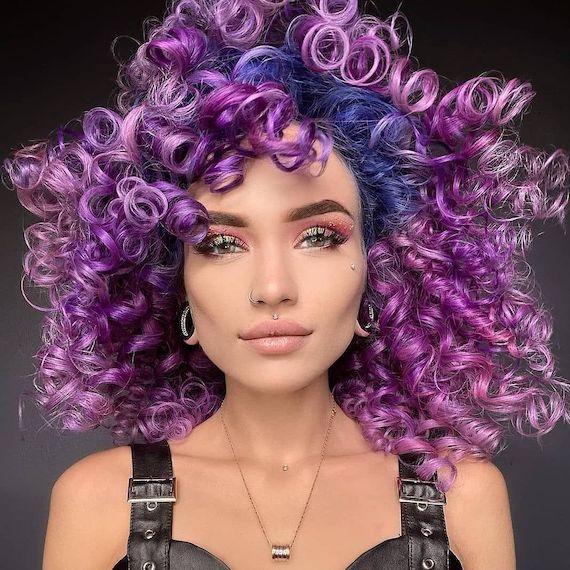 Model with curly, voluminous, purple hair featuring a blue color block.