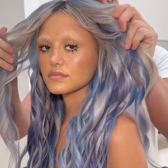Model with long, curled, silver hair, featuring frosty blue and lilac highlights.