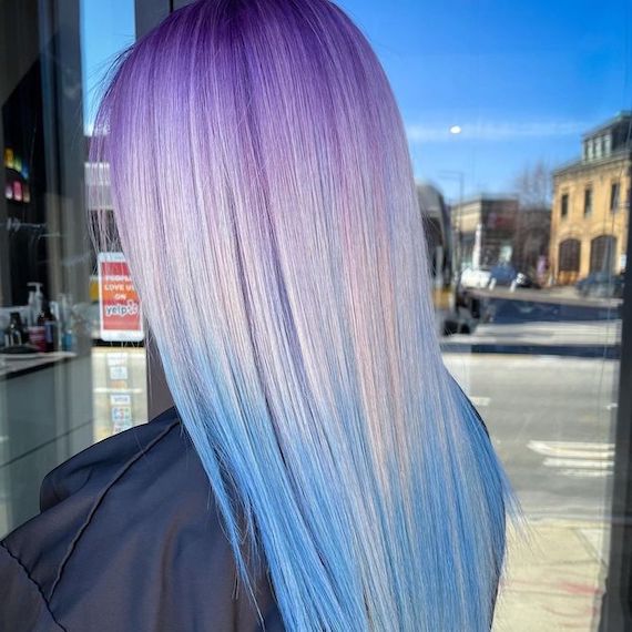 Model with long, straight hair, featuring a purple to platinum to blue ombre.
