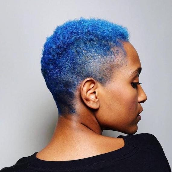 Side profile of woman with short, curly, bright blue hair, created using Wella Professionals.