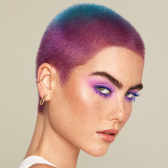 Model with very short, cropped pink and blue ombre hair faces the camera.