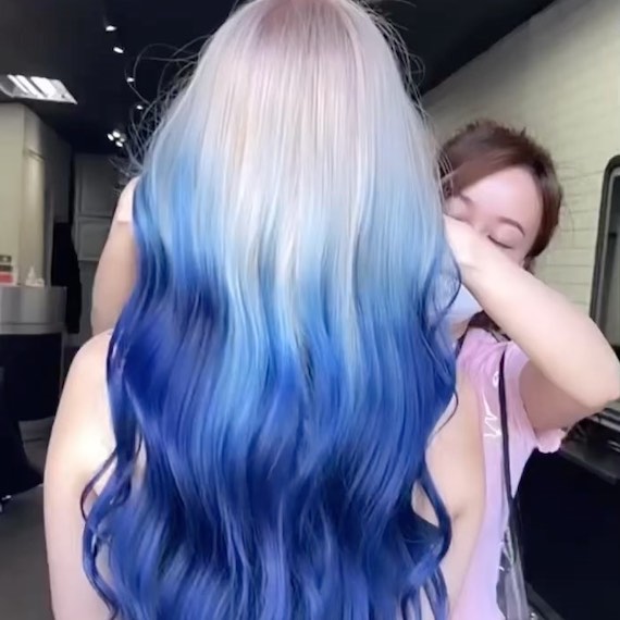 Back of model’s head with long, wavy, icy blonde to cobalt blue ombre hair.
