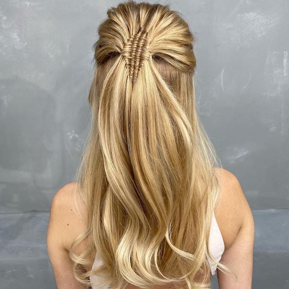 Hinterkopf einer Frau mit langen, glatten, blonden Haaren in einem halb hochgesteckten Zopf, kreiert mit Wella Professionals.