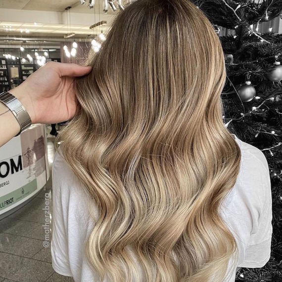Back of woman’s head with wavy hair and beige blonde balayage, created using Wella Professionals.