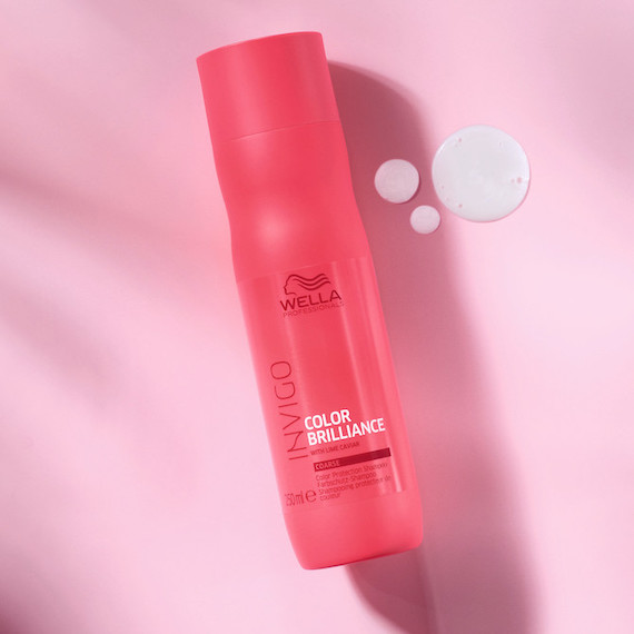 Bottle of Color Brilliance Shampoo on a pale pink background. 