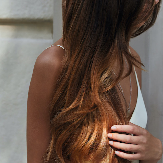 Model with long, caramel brown hair glistening in the sun.