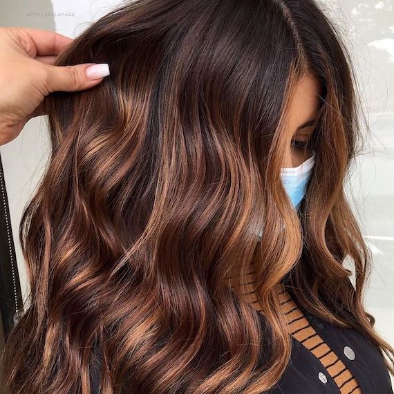 Side profile of model with long, dark brown hair and bronze balayage.