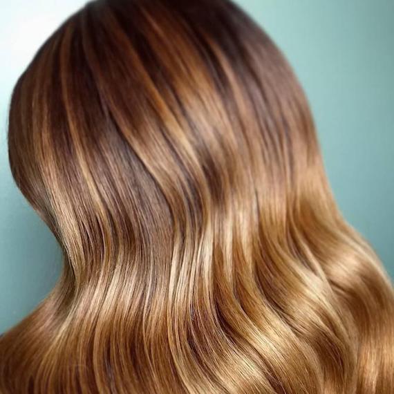 Back of woman’s head with wavy, honey brown hair, created using Wella Professionals.