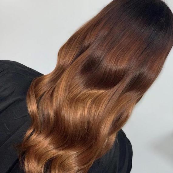 Back of head reveals long, wavy chocolate brown hair with lighter ends