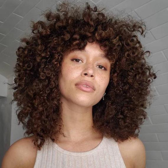 Woman facing camera with dark brunette curls, created using Wella Professionals.