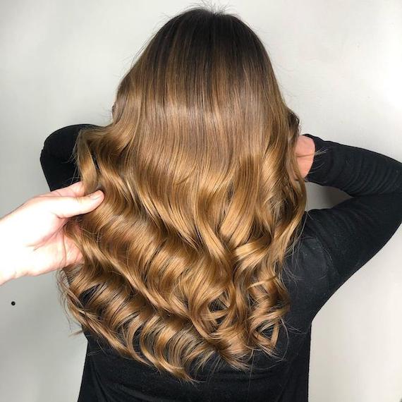 Back of woman’s head with loosely curled, caramel brown ombre hair, created using Wella Professionals.