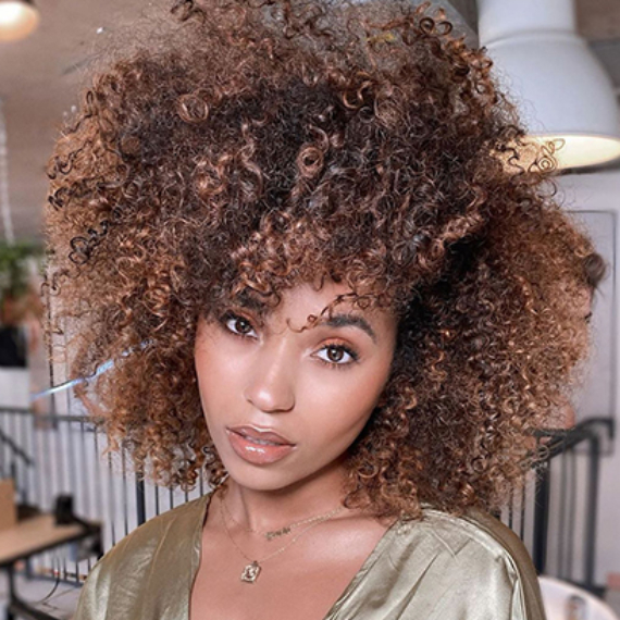 A model with very curly brown sugar colored hair