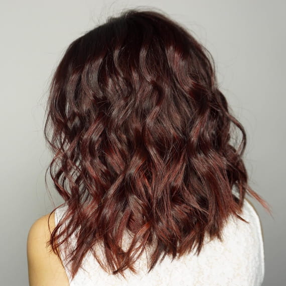 Woman with medium hair in burgundy illuminage, created with Wella Professionals