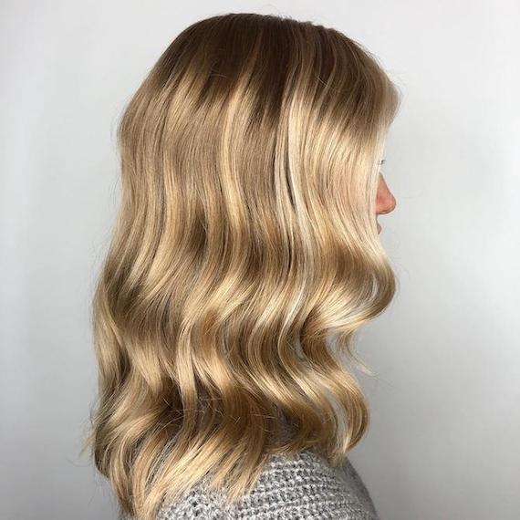 Side profile of woman with a root shadow and blonde babylights, created using Wella Professionals.