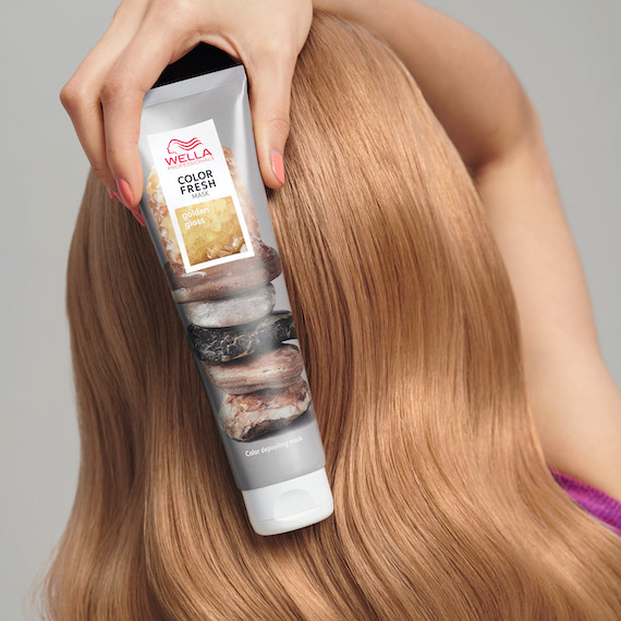 Model holds Color Fresh Mask in Golden Gloss in front of golden blonde, straight hair.