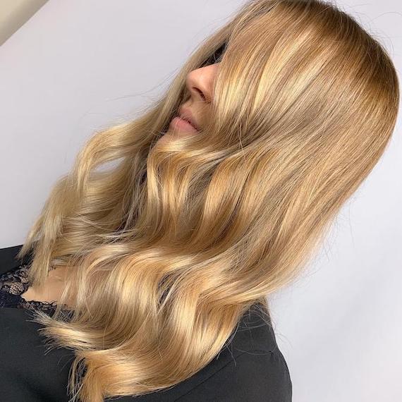 Side profile of woman with bright blonde hair and caramel highlights, created using Wella Professionals.