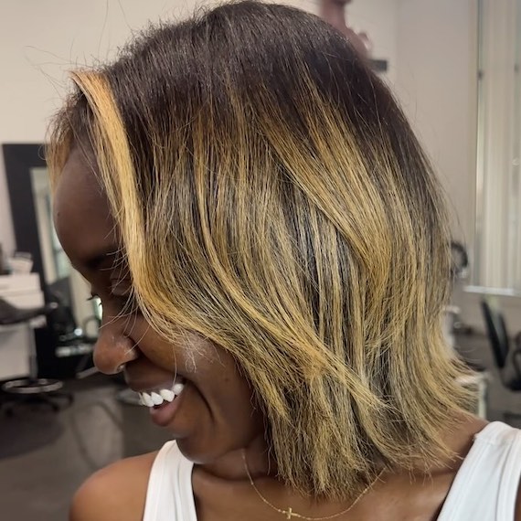 Dark brown hair with bold caramel face-framing highlights and a soft balayage.