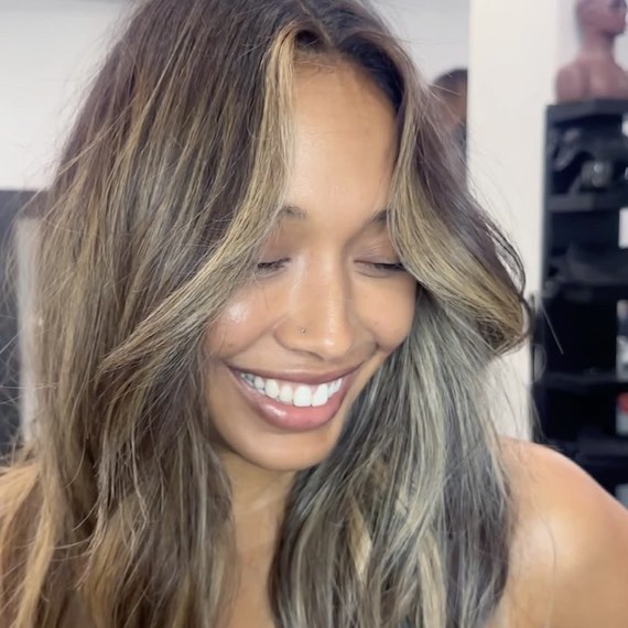 Caramel brown hair with a dark root melt and radiant bronde mid-length highlights.