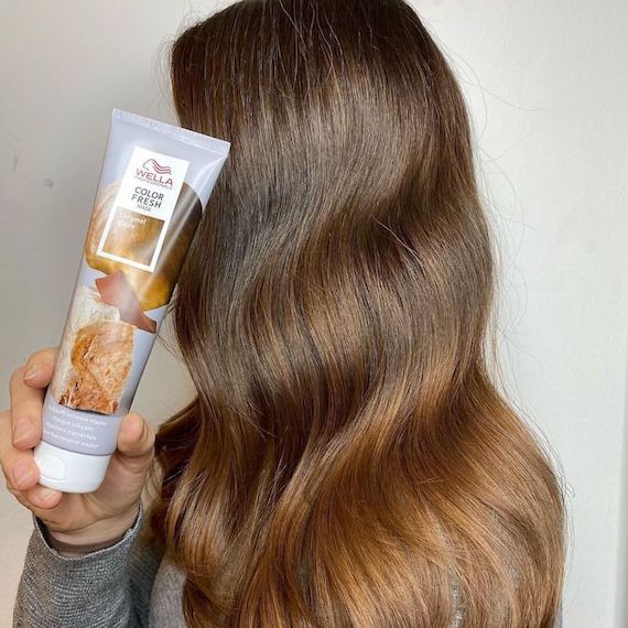 model with long, brown caramel sombre hair holds a Color Fresh Mask by Wella Professionals in front of their face