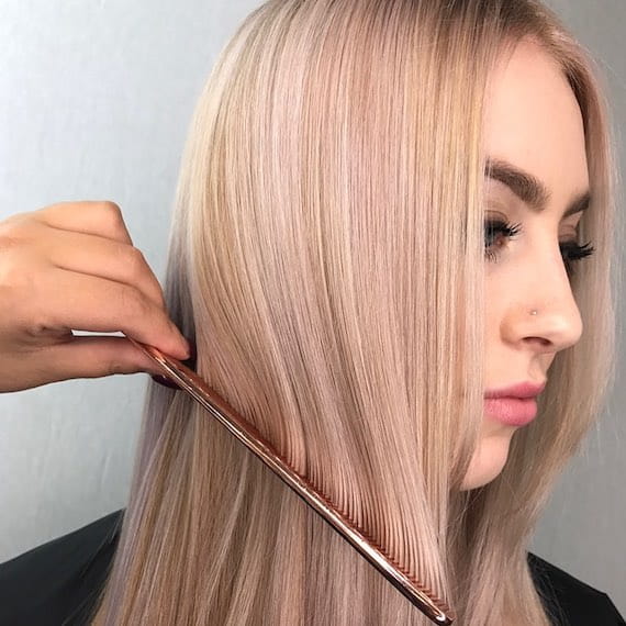 Photo of blonde woman having her long, straight hair combed, created using Wella Professionals.