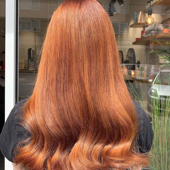 Photo of the back of a woman’s head with red hair styled in a bouncy blowdry style.