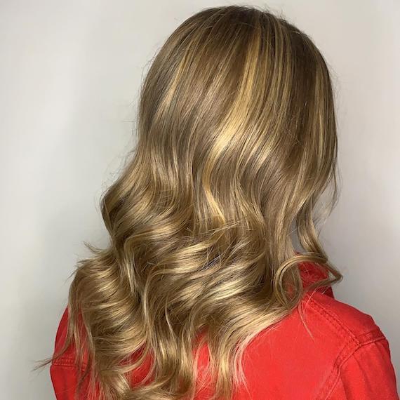 Image of the back of a woman’s head with powdered bronde hair color styled in loose waves.