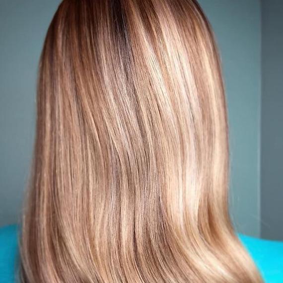 Close-up image of the back of a woman’s head with powdered blonde highlights on a dark blonde base.