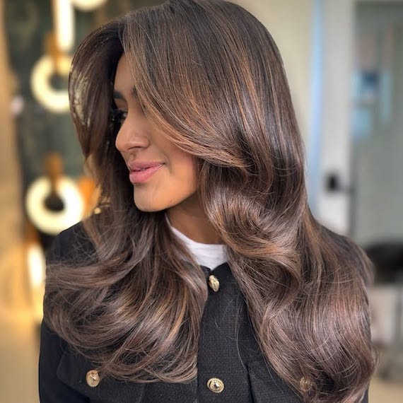 Chocolate brown hair with bronzy caramel highlights and a glossy finish.