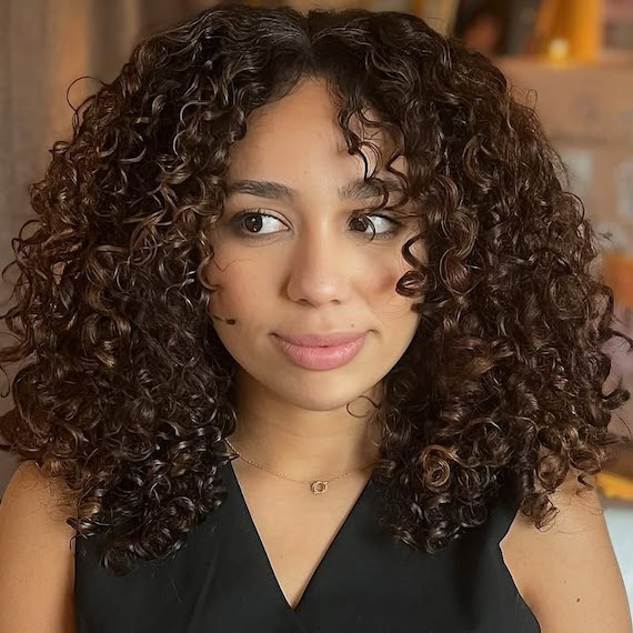 Dark hair with chocolate brown highlights and defined natural curls for added dimension.