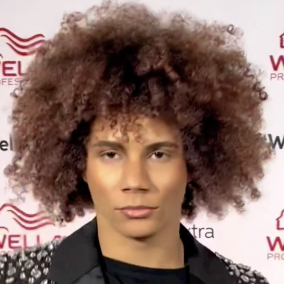 Headshot of a person with very curly chocolate brown hair