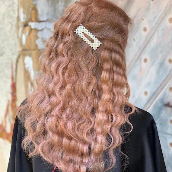 Back of a woman’s hair with tight waves and a pearl barrette, created using Wella Professionals.