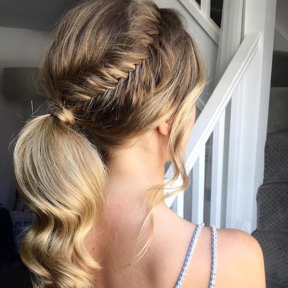 Photo of the back of a woman’s head with hair styled in a low ponytail and fishtail braid