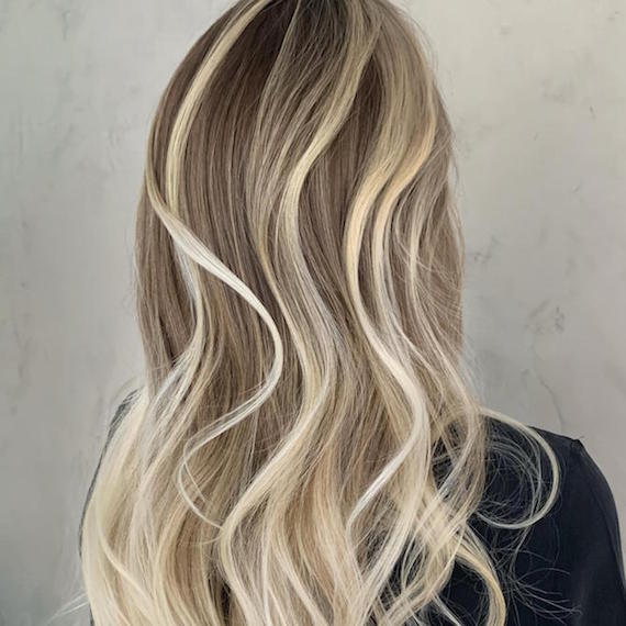 Back of woman’s head with chunky, platinum blonde highlights through long, wavy hair, created using Wella Professionals.