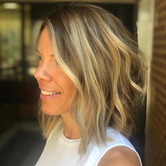 Side profile of woman with chunky highlights and lowlights through a blonde bob, created using Wella Professionals.