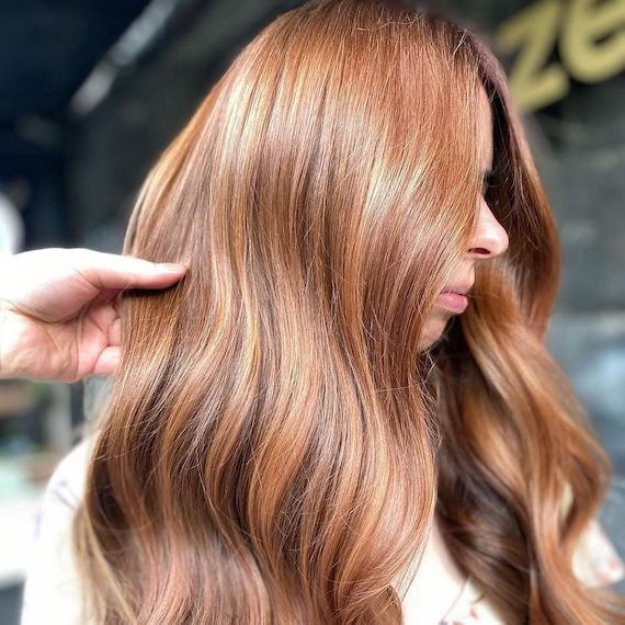 Side profile of model with long, wavy, honey cinnamon blonde hair.