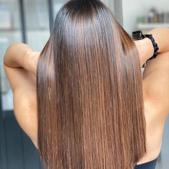 Back of woman’s head with poker straight, mocha brown hair, created using Wella Professionals.