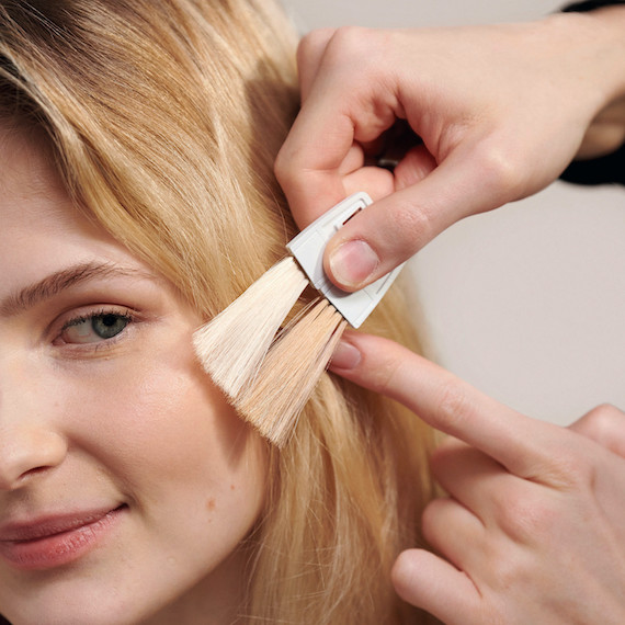 Hairdresser holds up colour swatches to compare with client’s skin tone.