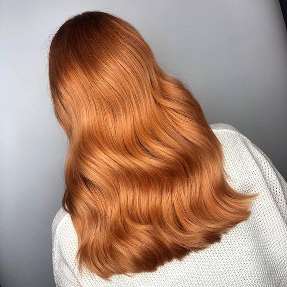 Back of woman’s head with long, wavy, copper red hair, created using Wella Professionals.