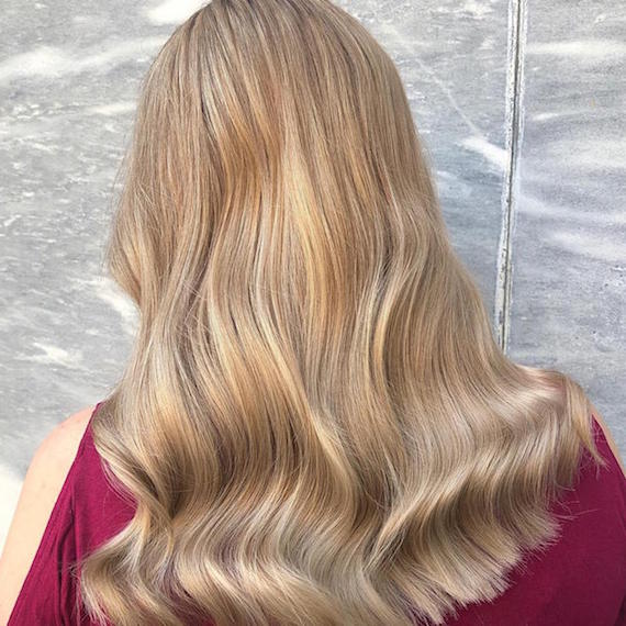 Back of woman’s head with long, wavy, creamy blonde hair, created using Wella Professionals.