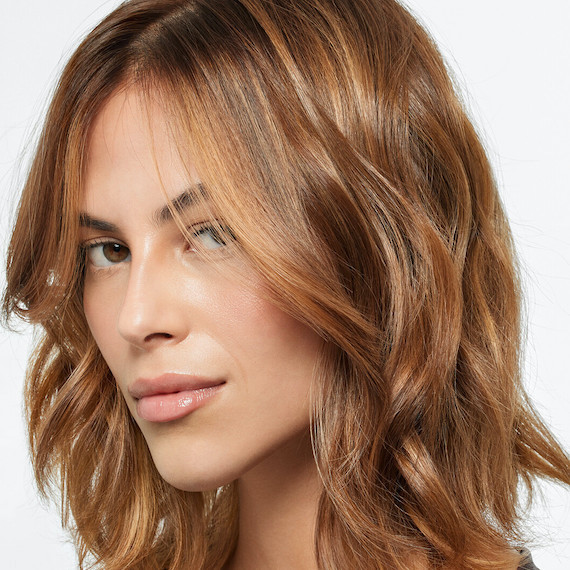 Model with mid-length, tousled, light brown hair featuring sun-kissed highlights.