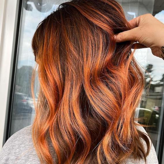 Hinterkopf einer Frau mit kupferfarbenem Balayage auf braunem Haar, erstellt mit Wella Professionals.