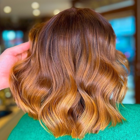 Copper blonde ombre hair with dark roots and lighter ends on brunette hair.