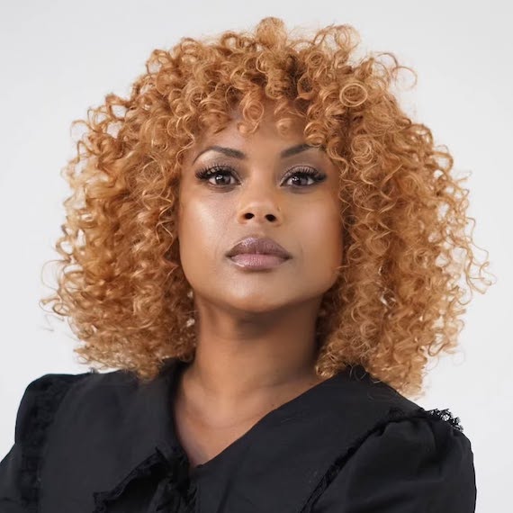 Curly copper honey blonde hair with warm highlights and volume.